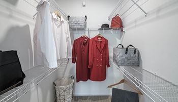 A walk in closet filled with clothes and bags